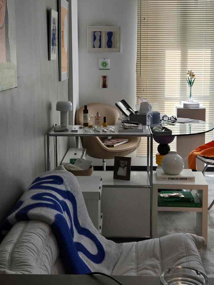 ナチュラルトーンの一人暮らしリビング、ソファとアームチェア、ガラステーブル、調和の取れた照明がある雰囲気の良い空間