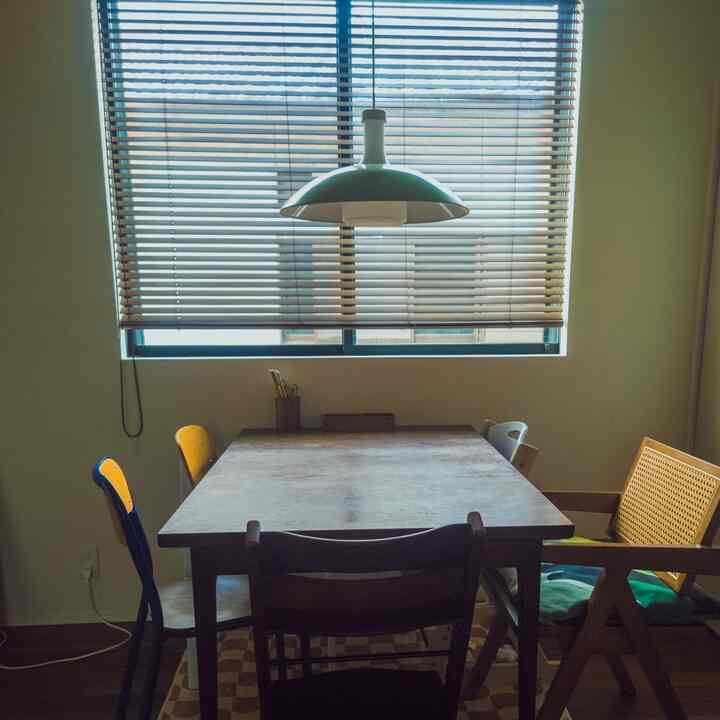 ウッドトーンとヴィンテージスタイルのダイニング、ブラインドとペンダントライトが配置された雰囲気のあるインテリア