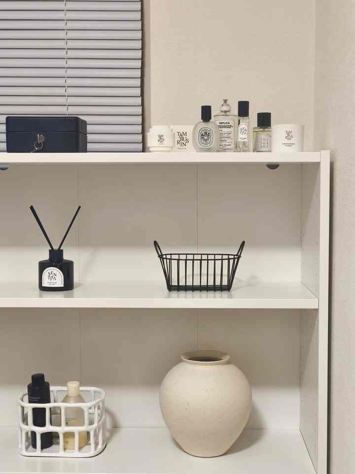 White and black toned single household 1K space featuring shelves with perfume bottles, diffuser, and ceramic vase in a simple natural interior