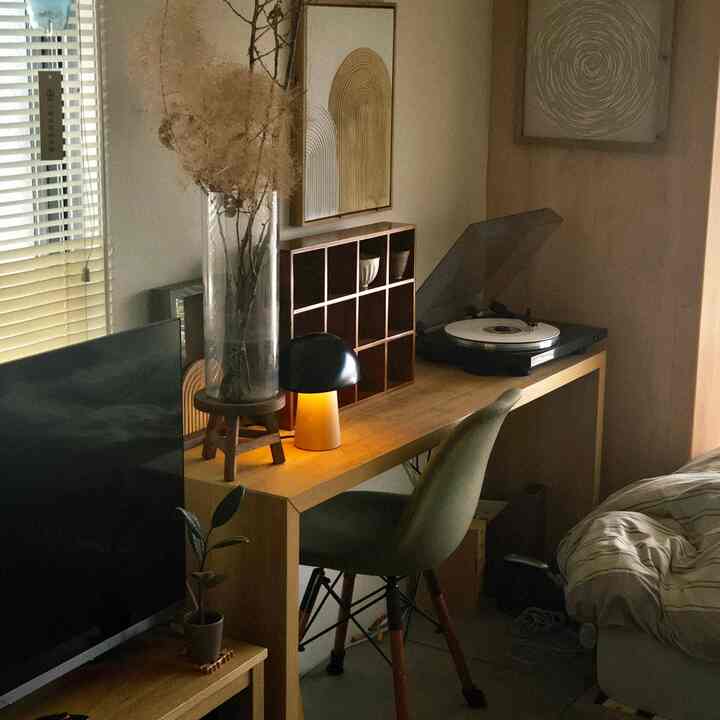 Natural wood tone bedroom and home office for single household featuring black table lamp and compact furniture