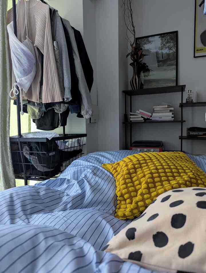 青のストライプ寝具と黄色いクッションが置かれた寝室、モダンな韓国インテリアの雰囲気ある空間