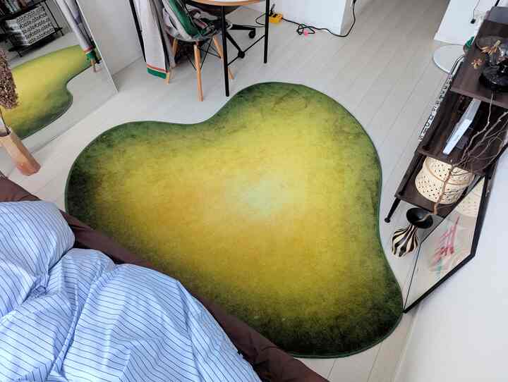 Minimal bedroom space featuring a green gradient rug and blue striped duvet cover with a full-length mirror and desk