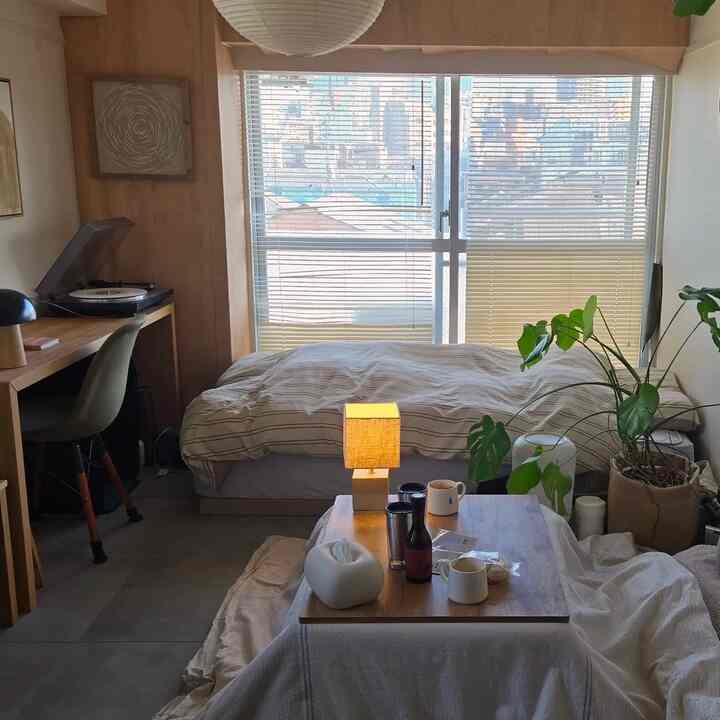 A softly lit Nordic-style studio apartment for a single household featuring wooden furniture and beige bedding creating a cozy atmosphere