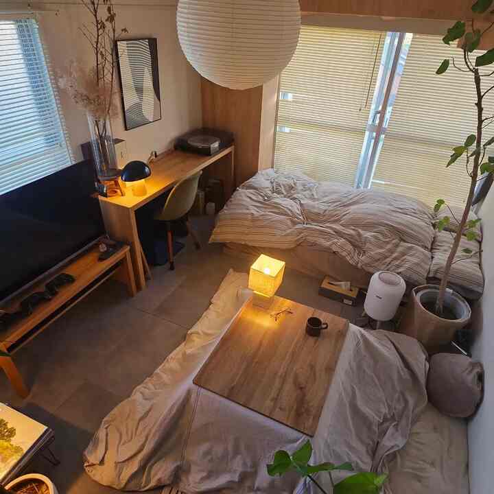 ベージュと木目調の一人暮らしワンルーム、ベッドとデスク、コーヒーテーブルが配置されたナチュラルモダンなインテリア