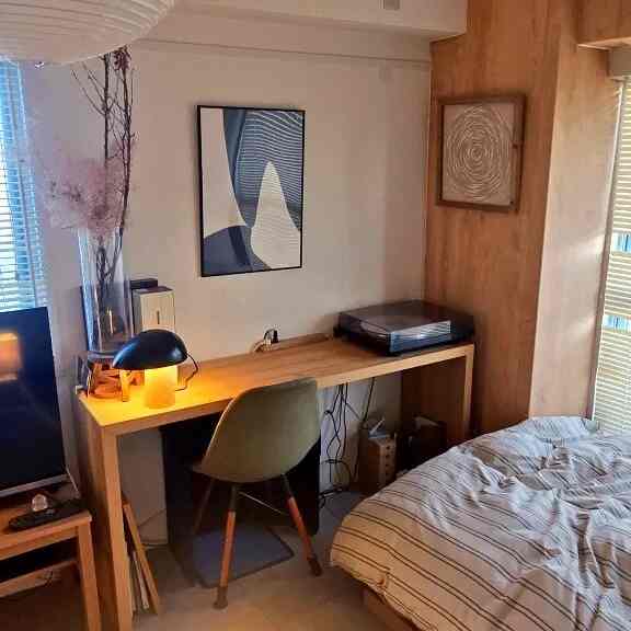 ナチュラルな色調のワンルーム寝室、木製のデスクとベッドが配置された雰囲気のある作業空間