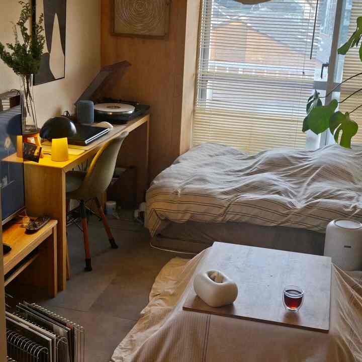 Cozy small single bedroom with warm wood tones and natural light, featuring a multifunctional desk and kotatsu table