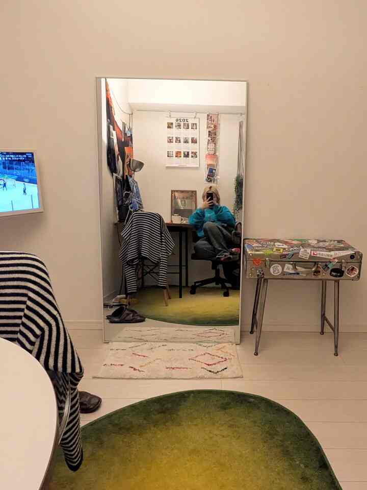 ナチュラルトーンの狭い一人暮らし部屋、全身鏡とイエローグリーンのラグが配置されたシンプルなインテリア