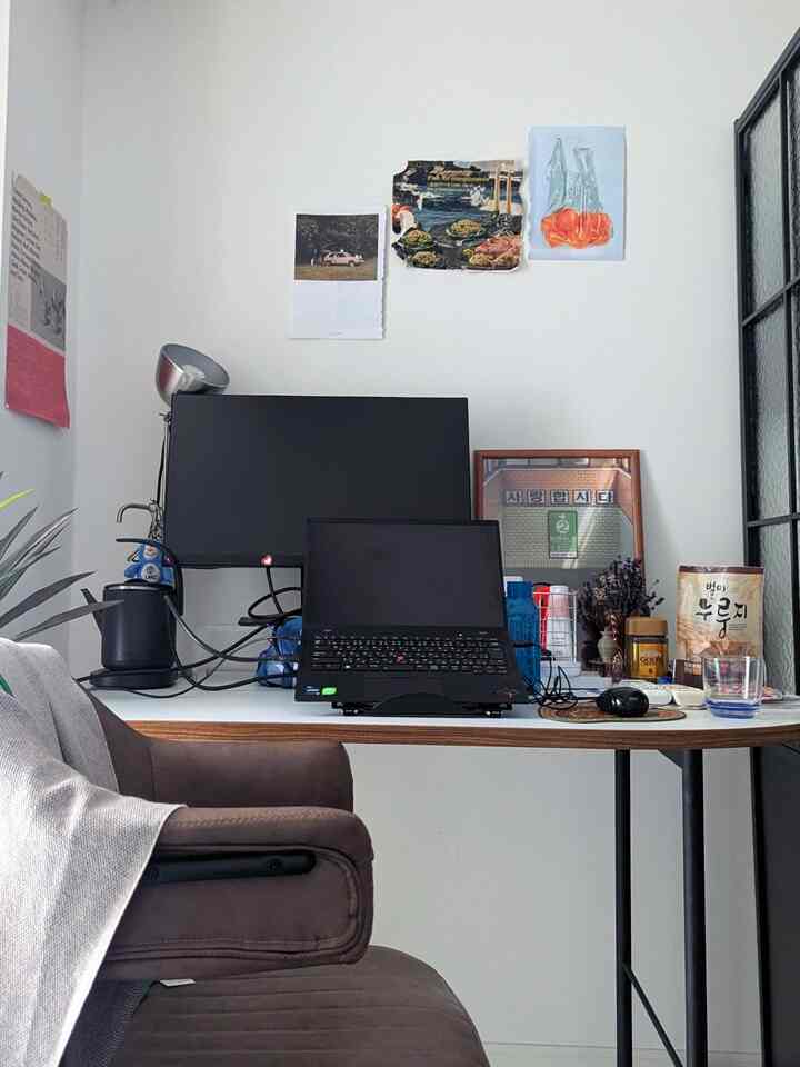 白い壁とブラウンの椅子が配されたホームオフィスのワークスペース、デスクにはノートパソコンとモニターが置かれた清潔感のある空間