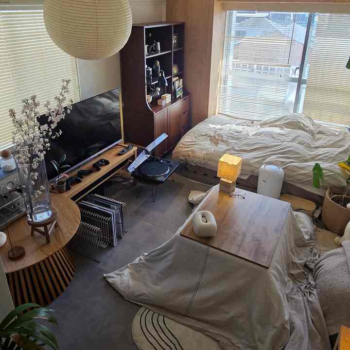 ベージュとブラウン調のワンルーム寝室、こたつテーブルと桜の飾りが調和する温かみのある空間