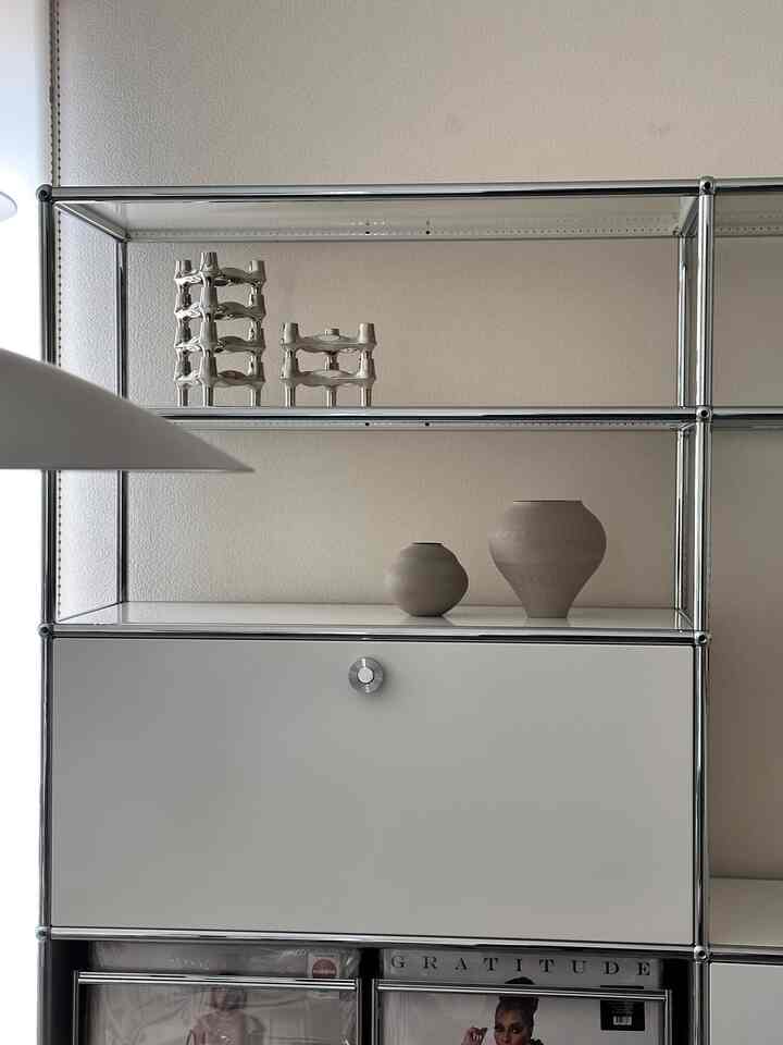 白とシルバーのトーンでモダンな収納棚、シンプルなオブジェが配置されたミニマルなインテリア空間