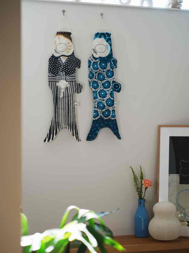 ナチュラルカラーの壁の玄関スペース、壁に赤と青の文様の飾りと青い花瓶と照明が配置された温かみのあるシンプルな雰囲気