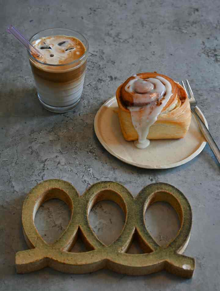 グレーのコンクリートテーブルにベージュの皿とおうちカフェのドリンクが配置された雰囲気のあるインテリア