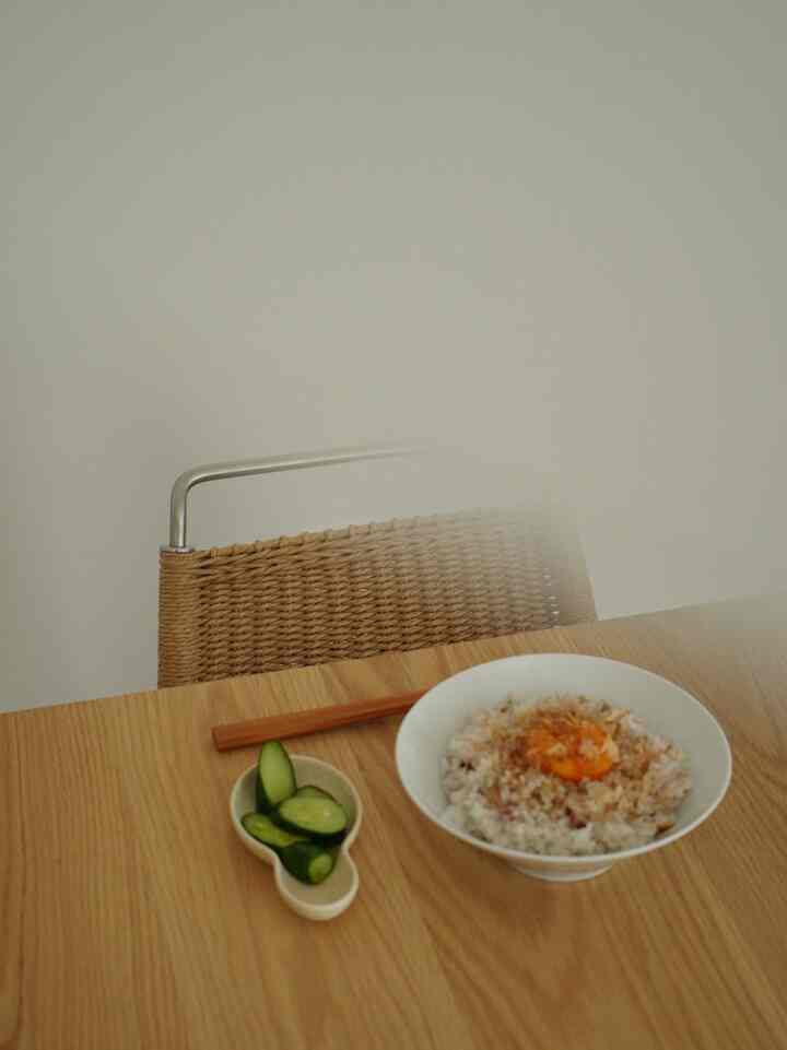 ナチュラルな色調のダイニング、木目調のテーブルと編み込みチェアが印象的な空間