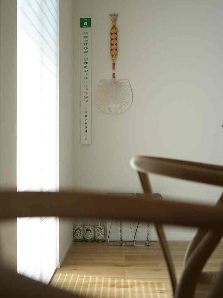 ナチュラルカラーのリビングルーム、白い壁と木の床、ダイニングチェアの一部が見える清潔感のある空間