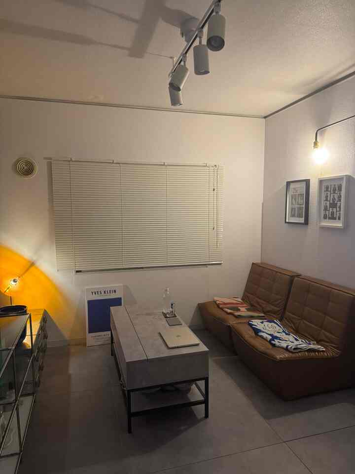 Modern living room with white walls and a brown leather sofa, central concrete-tone coffee table, and diverse lighting fixtures