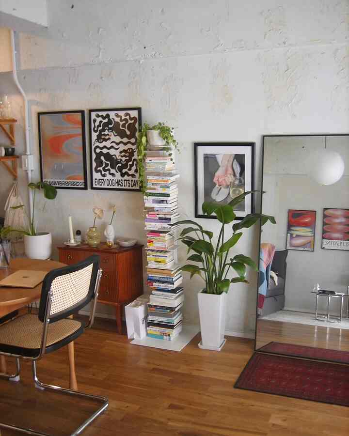 ナチュラルな木目調の床にダイニングテーブル、ポスターと本棚、観葉植物が配置されたナチュラルモダンなリビング