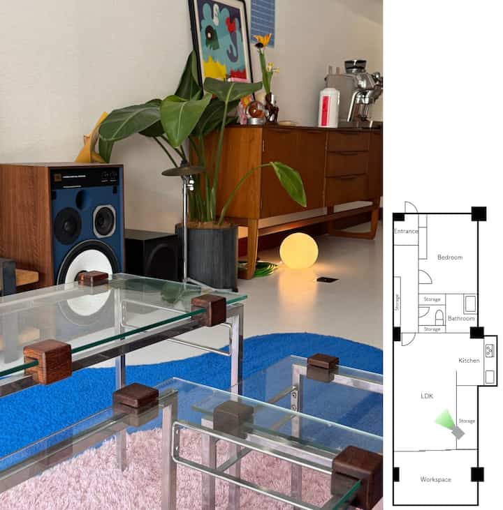 ナチュラルな木目調と青いラグのリビング、ヴィンテージのガラステーブルと植物が配置された雰囲気のあるインテリア