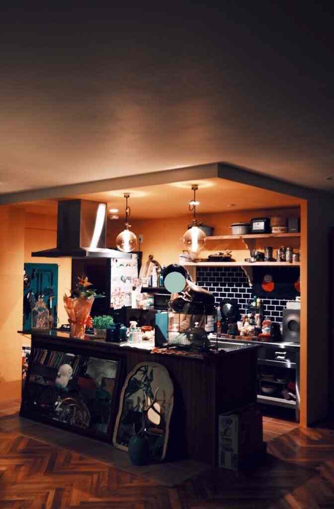 暖かいオレンジとブラウンの色調のキッチンとダイニング、UFO型ペンダントライトが印象的な雰囲気を演出する空間