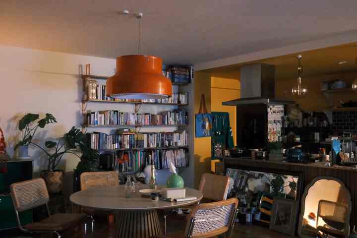 温かみのあるブラウンとオレンジのダイニングルーム、中央にオレンジのペンダントライトとラタンのダイニングチェアが配置された雰囲気のある空間