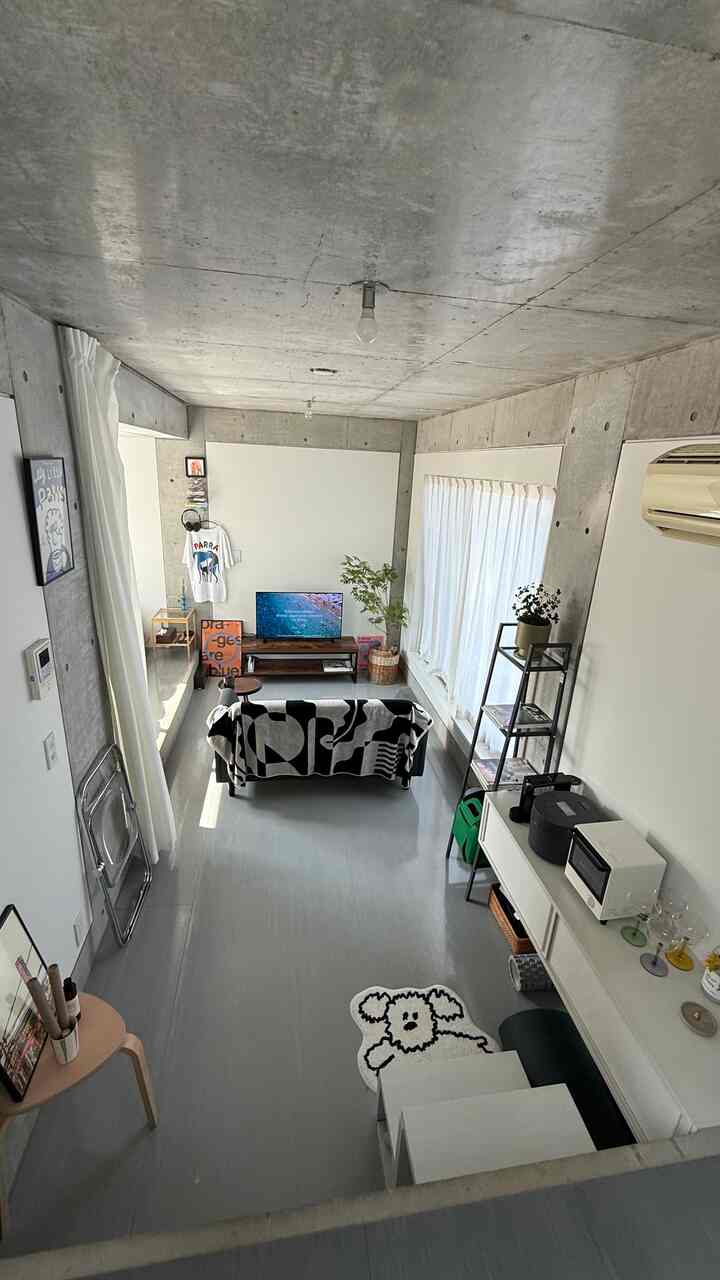 グレーの床と白い壁、黒と白の柄のソファ、テレビ台が配置されたミッドセンチュリーモダンなダイニングルーム