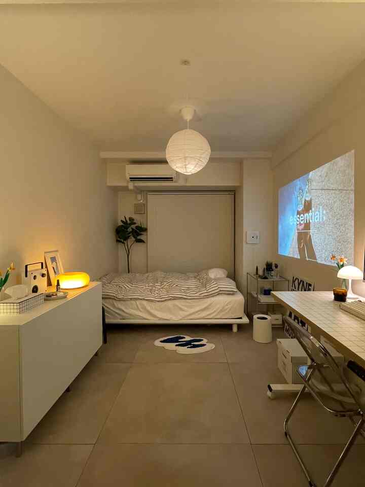 白とベージュのトーンの6畳の寝室、シンプルなナチュラルモダンスタイルで机とペンダントライトが配置された落ち着いた空間