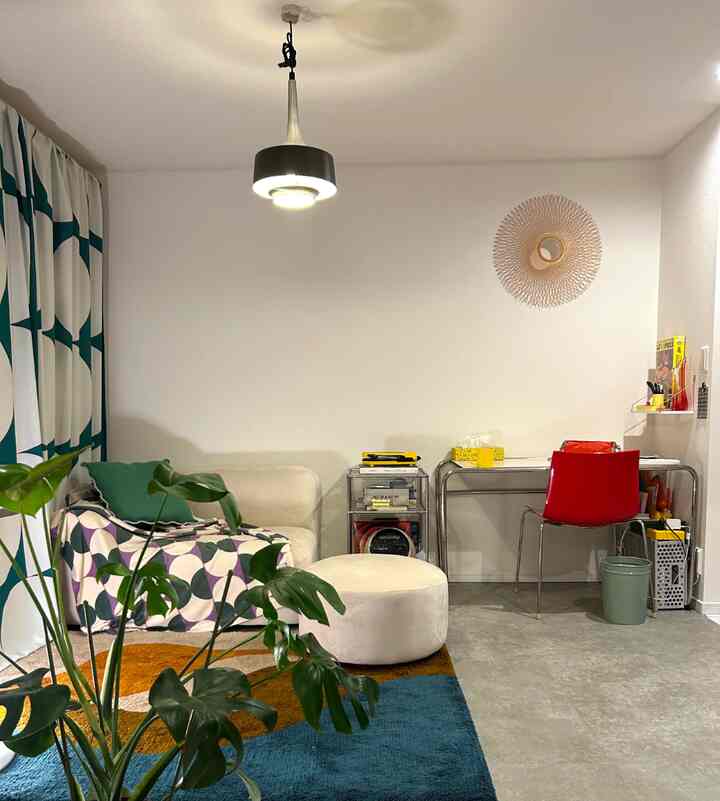 白と赤のアクセントがあるミッドセンチュリーモダンのリビング、ソファとデスク、植物が配置された雰囲気のある空間