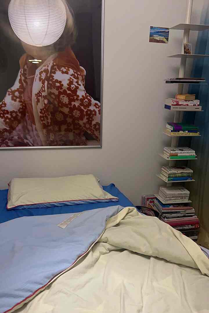 青とベージュの寝具が置かれた6畳の寝室、右側に本棚と壁にウォールアートが配置された雰囲気のよい空間