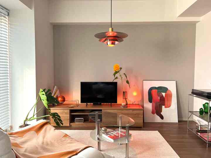 温かみのあるウッドトーンとオレンジ、グリーンが調和したナチュラルモダンなリビング、整った家具と柔らかな照明の印象的な空間