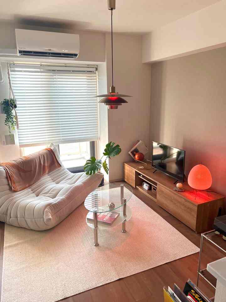 ホワイトとブラウンのトーンのリビング、快適なソファとコーヒーテーブル、自然光と植物が調和した雰囲気のあるインテリア