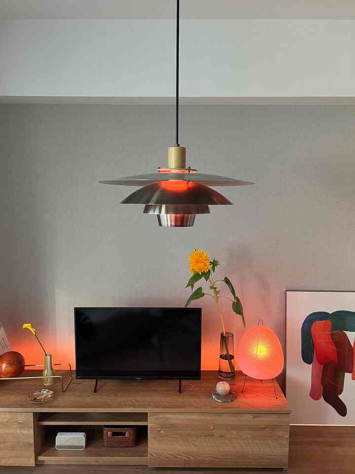 ナチュラルカラーとベージュのトーンが調和したリビング、ミッドセンチュリーモダンスタイルのペンダントライトと花瓶、テーブルランプが温かみのある雰囲気を演出する空間