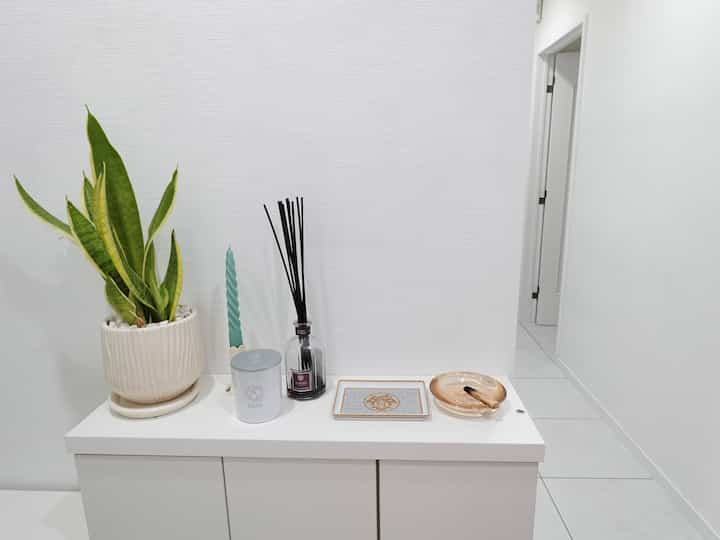 白と緑のトーンの玄関、狭い空間に設置された浅い収納棚がすっきりとした印象のインテリア。