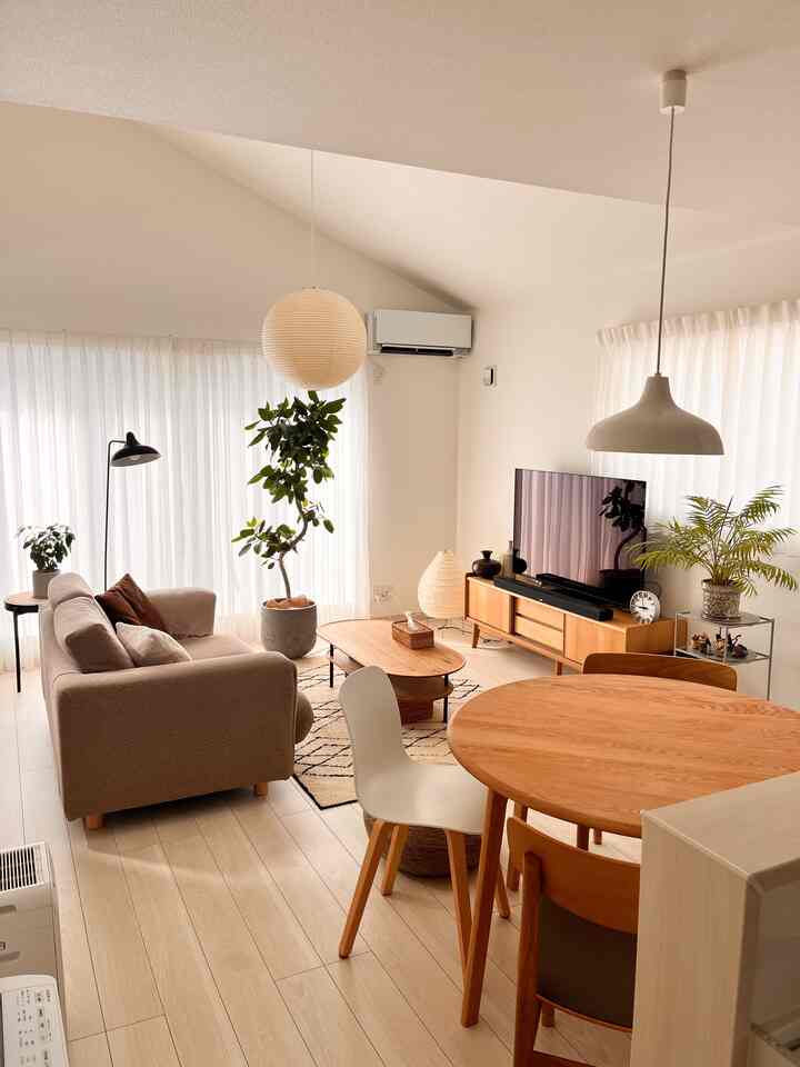 明るいアイボリー色の壁と木目調の家具、自然なソファが配置されたナチュラルスタイルの二人用リビングダイニングスペース