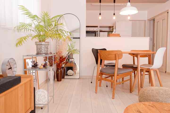 ナチュラルな木目調と白を基調としたリビング・ダイニング、アーチ型の大きな鏡と植物が配置された広々とした印象的な空間