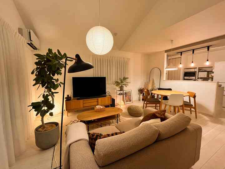 暖かいベージュとナチュラルウッドの色調が印象的なリビング・ダイニングルーム、ペンダントライトとフロアランプが配置された雰囲気のある空間