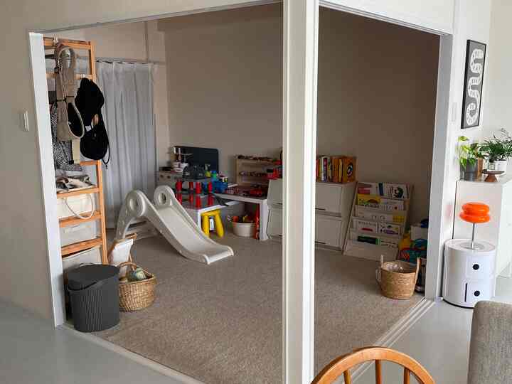 ベージュとナチュラルカラーの子供部屋、すべり台と収納が配置された雰囲気のある遊び場