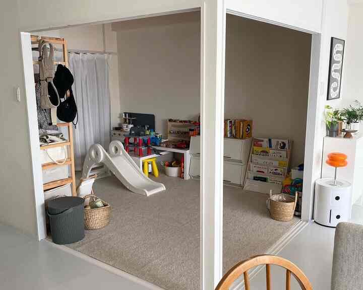 ベージュのカーペットと白い家具が配置された子供部屋と隣接するリビングスペースの雰囲気のあるインテリア