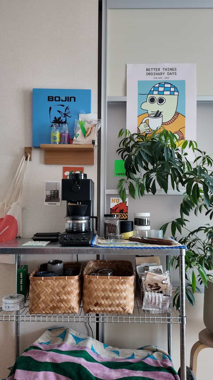 ナチュラルモダンな雰囲気のホームカフェ空間。シルバーのメタル棚とナチュラルウッドの壁掛けフック、緑豊かな植物が配置された印象的なインテリア