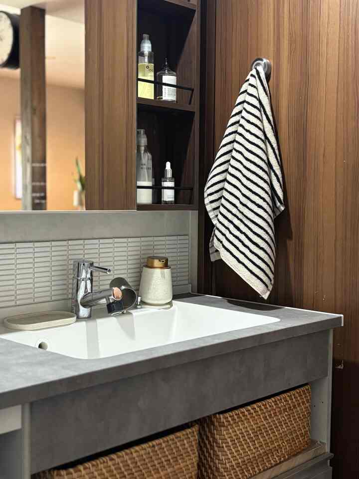 白い洗面台とブラウンの木目調が調和するモダンで自然な雰囲気のバスルーム