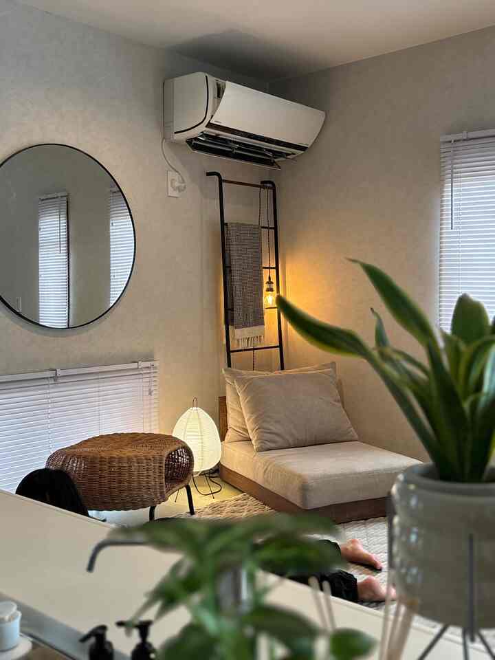 白とベージュのトーンの玄関、丸い鏡とラタンのスツール、ペンダントライトが配置された雰囲気のあるインテリア