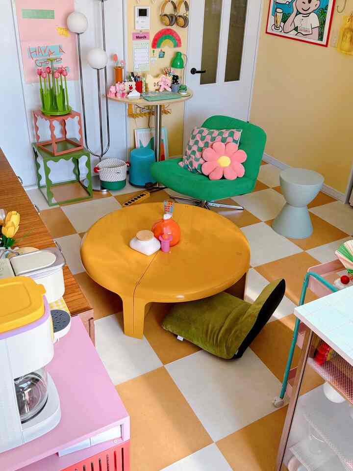 黄色と緑の色調のリビング、丸い黄色のテーブルと緑のアームチェアが配置された印象的な空間