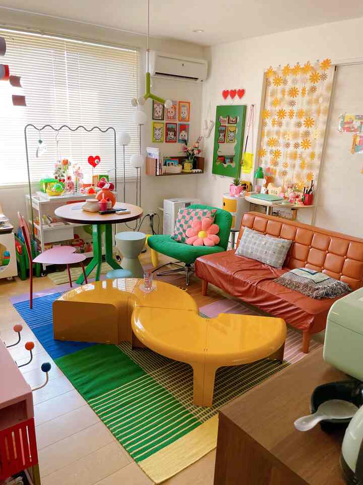 明るくカラフルな子供部屋風リビング、茶色いソファと黄色いテーブル、子供の玩具や収納アイテムが配置された雰囲気のある空間