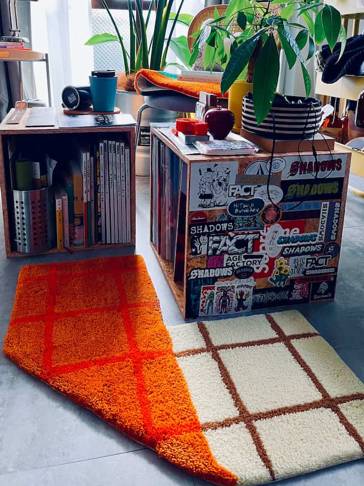 オレンジと木目調のL字型リビング、レコードボックスと植物が配置されたレトロで雰囲気のあるインテリア