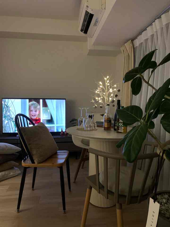 温かみのあるブラウンとブラックの色調が特徴のダイニング、食卓と椅子、テレビ台、照明が配置された雰囲気のあるインテリア