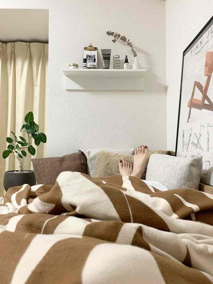 ブラウンとベージュのトーンのリビング、居心地の良いクッションとパターン入りのブランケットが配置された暖かな雰囲気のあるインテリア