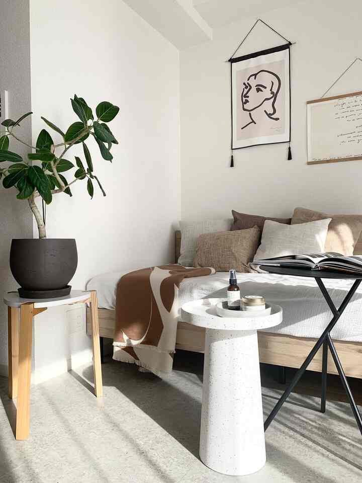 ナチュラルな色調のリビング、木製サイドテーブルに植物を置き、ソファベッドとクッションが居心地の良い読書空間を演出している