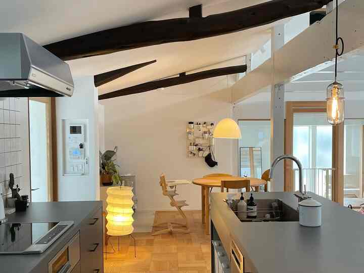 白と木目調が調和したキッチンとダイニング、丸テーブルとチェア、ペンダントライトが配置された雰囲気のあるナチュラルモダンなインテリア