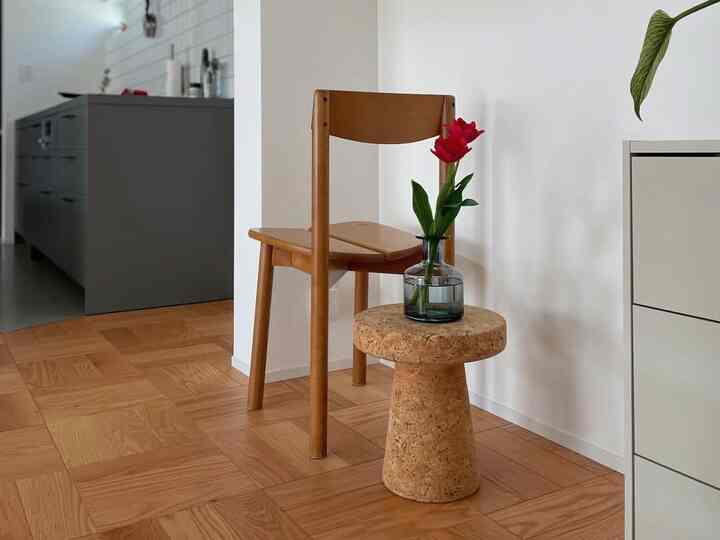 ナチュラルな木目調とコルク素材を活かしたキッチン、赤い花が飾られたサイドテーブルが印象的な温かみのあるインテリア