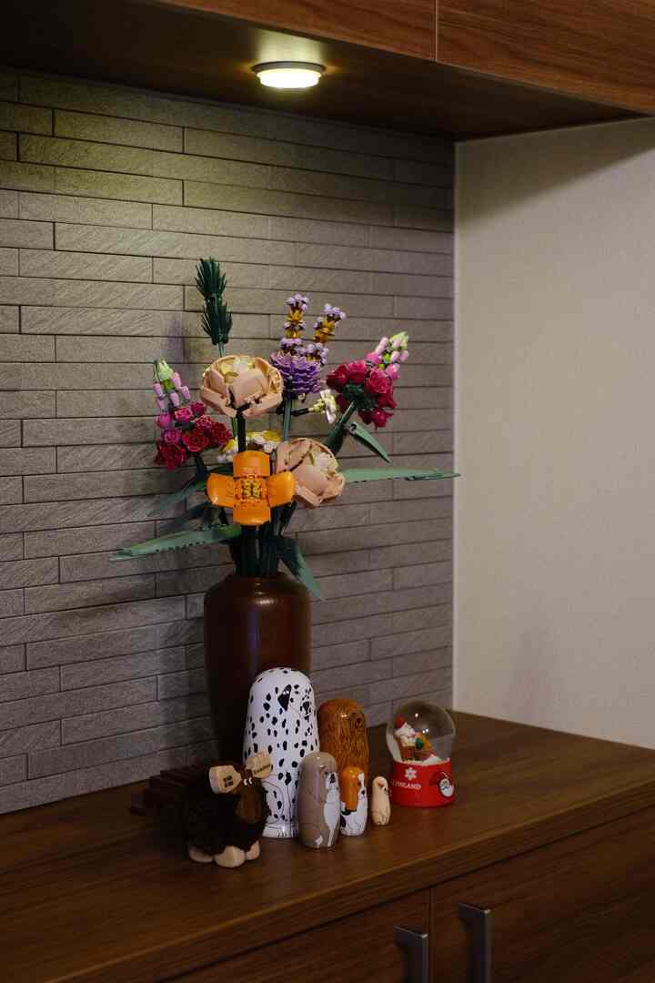 木目調と弱い日当たりの玄関スペース、レゴの花とマトリョーシカのオブジェが配置された雰囲気のあるインテリア