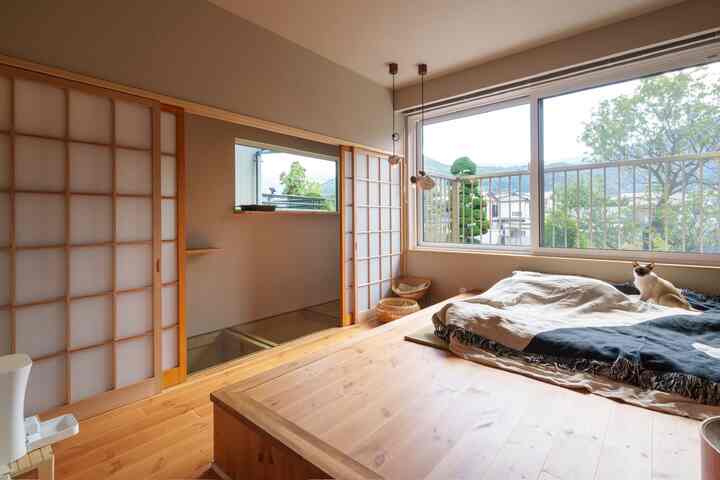 ナチュラルな木目調の寝室、大きな窓と猫がくつろぐ温かみのあるインテリア