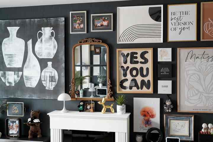 ゴールドとホワイトが調和したリビングの壁面、様々な額縁と大きなゴールドミラーが配置されたモダンなホームギャラリーのインテリア